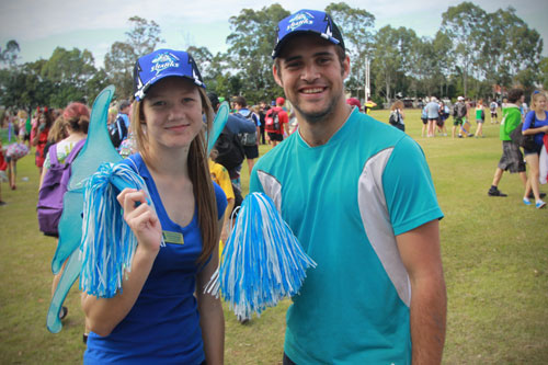 Male and female student in sports uniform standing on sport grounds.