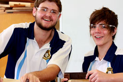 Two male students with safety glasses on.